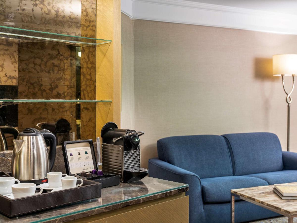 Radisson Blu Hotel, Istanbul Sisli Exterior photo The photo shows a small, elegantly designed living area. On the left, there is a glass shelf with a stylish electric kettle, several white cups, and a coffee machine. Next to these items, there is a tray, suggesting a setup for making drinks. To the 